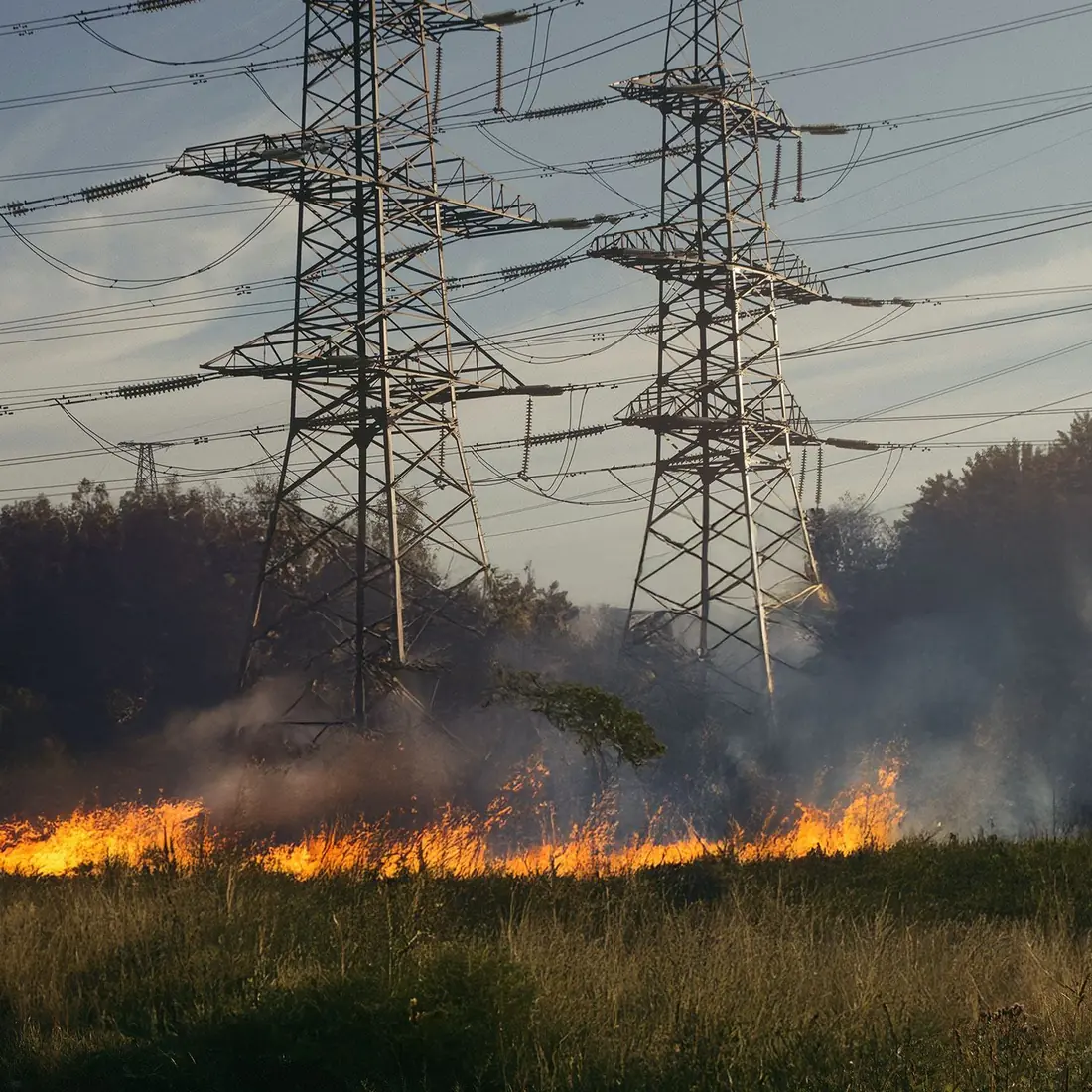 Grass fire burning under transmission towers
